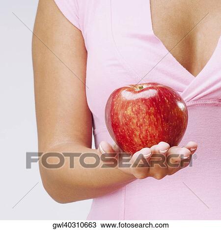 Mid section view of a woman holding an apple View Large Photo Image Stock Image - Mid section view of a woman holding an apple. Fotosearch