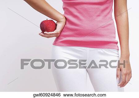Mid section view of a woman holding an apple View Large Photo Image Stock Photograph - Mid section view of a woman holding an apple . Fotosearch