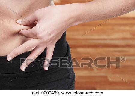 Mid section view of a woman pinching her waist View Large Photo Image Stock Photo - Mid section view of a woman pinching her waist. Fotosearch