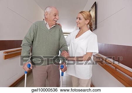 Stock Photograph - Nurse assisting a man to walk. Fotosearch