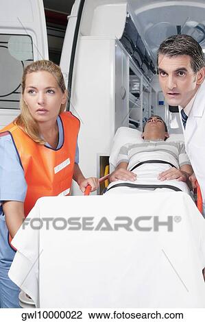 Paramedics leading a patient on a gurney from an ambulance View Large Photo Image Stock Image - Paramedics leading a patient on a gurney from an ambulance. Fotosearch