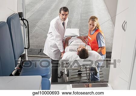 Paramedics leading a patient on a gurney into an ambulance View Large Photo Image Stock Image - Paramedics leading a patient on a gurney into an ambulance. Fotosearch