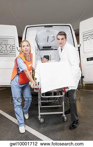 Paramedics leading a patient on a gurney from an ambulance View Large Photo Image Stock Image - Paramedics leading a patient on a gurney from an ambulance. Fotosearch
