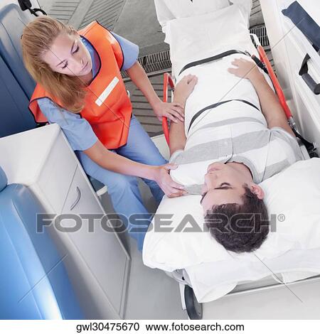 Paramedics leading a patient on a gurney into an ambulance View Large Photo Image Stock Image - Paramedics leading a patient on a gurney into an ambulance. Fotosearch