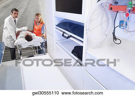 Paramedics leading a patient on a gurney into an ambulance View Large Photo Image Stock Image - Paramedics leading a patient on a gurney into an ambulance. Fotosearch