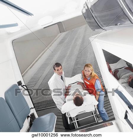 Paramedics leading a patient on a gurney into an ambulance View Large Photo Image Stock Photograph - Paramedics leading a patient on a gurney into an ambulance. Fotosearch