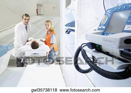 Paramedics pushing a patient on a gurney from an ambulance View Large Photo Image Stock Photo - Paramedics pushing a patient on a gurney from an ambulance. Fotosearch