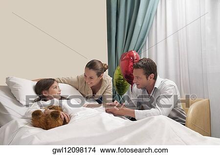 Parents with their daughter in a hospital ward View Large Photo Image Picture - Parents with their daughter in a hospital ward. Fotosearch