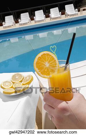 Person's hand holding a glass of orange juice View Large Photo Image Stock Image - Person's hand holding a glass of orange juice. Fotosearch