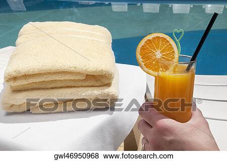 Stock Photo - Person's hand holding a glass of orange juice. Fotosearch