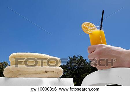 Stock Photograph - Person's hand holding a glass of orange juice. Fotosearch