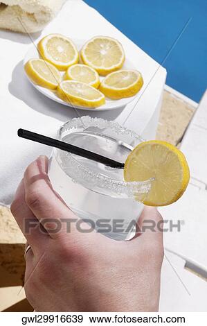 Person's hand holding a glass of lemonade View Large Photo Image Stock Photo - Person's hand holding a glass of lemonade. Fotosearch