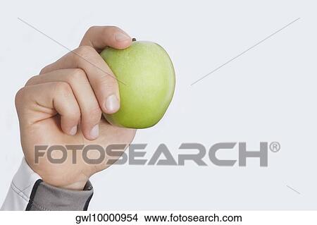 Person's hand holding a green apple View Large Photo Image Picture - Person's hand holding a green apple. Fotosearch