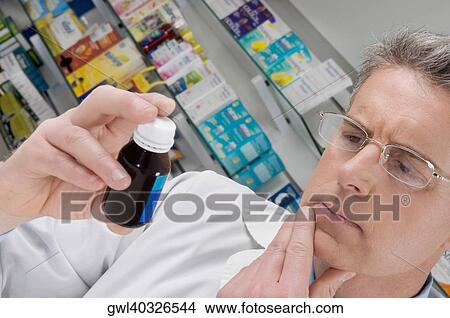Pharmacist holding a medicine bottle and thinking View Large Photo Image Picture - Pharmacist holding a medicine bottle and thinking. Fotosearch
