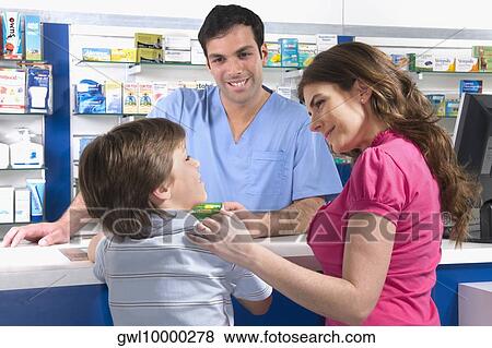 Pharmacist looking at boy standing with his mother View Large Photo Image Stock Photo - Pharmacist looking at boy standing with his mother. Fotosearch