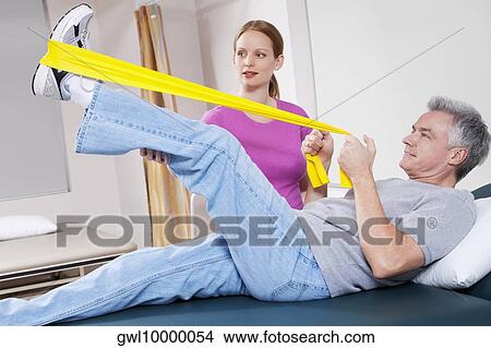 Picture - Physiotherapist assisting a patient in exercising. Fotosearch