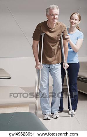 Physiotherapist assisting a patient in walking with crutches View Large Photo Image Stock Image - Physiotherapist assisting a patient in walking with crutches. Fotosearch
