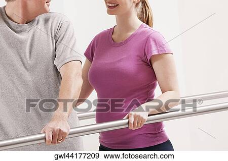 Stock Photo - Physiotherapist assisting a patient in walking. Fotosearch