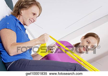 Physiotherapist assisting a patient in exercising View Large Photo Image Stock Photography - Physiotherapist assisting a patient in exercising. Fotosearch