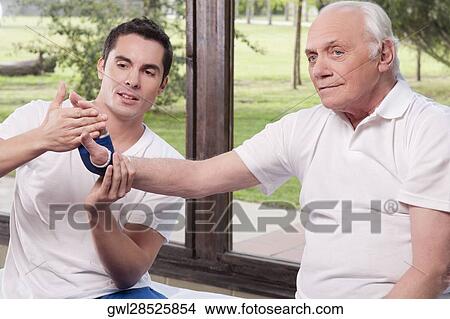 Picture - Physiotherapist examining a man's hand. Fotosearch