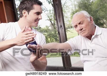 Physiotherapist examining a man's hand View Large Photo Image Stock Photo - Physiotherapist examining a man's hand. Fotosearch