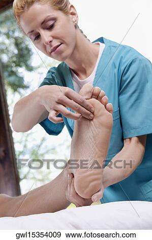 Physiotherapist examining the foot of a patient View Large Photo Image Stock Photo - Physiotherapist examining the foot of a patient. Fotosearch