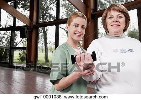 Stock Photo - Physiotherapist helping a disabled woman in exercising. Fotosearch