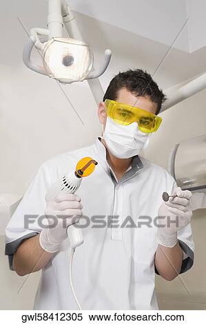 Stock Photography - Portrait of a dentist holding dental equipments. Fotosearch