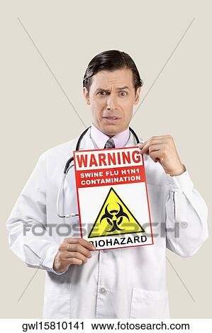 Stock Image - Portrait of a doctor showing a Biohazard warning sign. Fotosearch