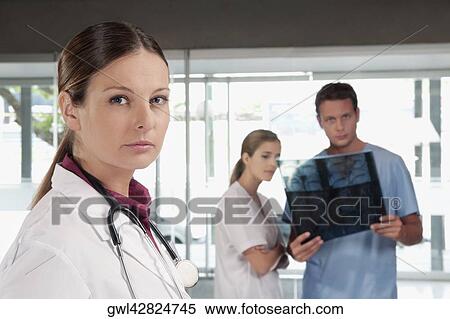 Portrait of a female doctor with her colleagues in the background View Large Photo Image Stock Photography - Portrait of a female doctor with her colleagues in the background. Fotosearch