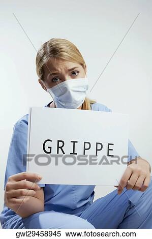 Stock Photography - Portrait of a female surgeon showing a placard with word GRIPPE written on it. Fotosearch