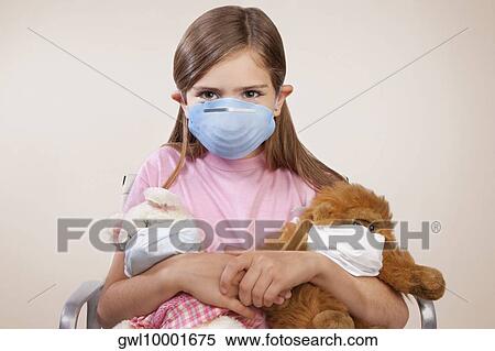 Stock Photography - Portrait of a girl wearing a flu mask and holding stuffed toys. Fotosearch
