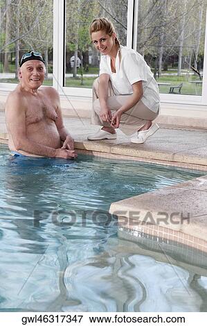 Portrait of a man in a swimming pool with a health worker at the poolside View Large Photo Image Stock Photo - Portrait of a man in a swimming pool with a health worker at the poolside. Fotosearch