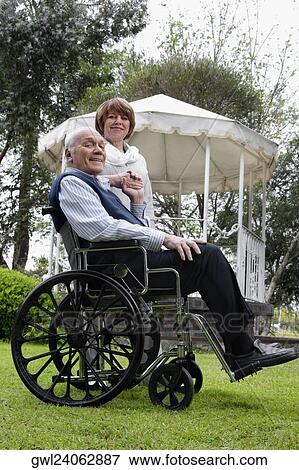 Portrait of a man sitting in a wheelchair with a woman standing beside him View Large Photo Image Stock Photo - Portrait of a man sitting in a wheelchair with a woman standing beside him. Fotosearch