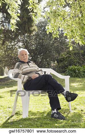 Portrait of a man sitting on a chair in a park View Large Photo Image Stock Image - Portrait of a man sitting on a chair in a park. Fotosearch