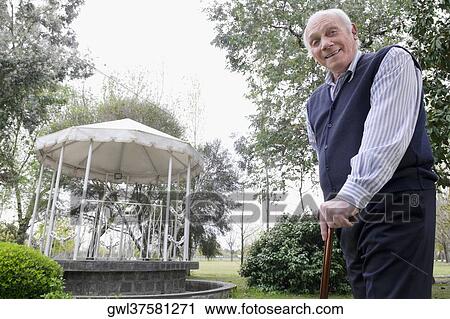 Portrait of a man standing in a garden with a cane View Large Photo Image Stock Image - Portrait of a man standing in a garden with a cane. Fotosearch