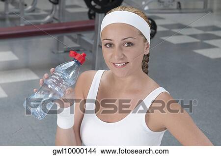 Portrait of a woman drinking water from a water bottle View Large Photo Image Picture - Portrait of a woman drinking water from a water bottle. Fotosearch