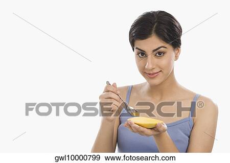Portrait of a woman eating mango with a spoon View Large Photo Image Stock Photo - Portrait of a woman eating mango with a spoon. Fotosearch