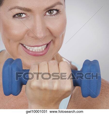 Stock Image - Portrait of a woman exercising with a dumbbell. Fotosearch