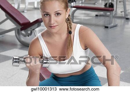 Portrait of a woman exercising with dumbbell in a gym View Large Photo Image Stock Image - Portrait of a woman exercising with dumbbell in a gym. Fotosearch
