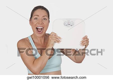 Portrait of a woman holding a bathroom scale and laughing View Large Photo Image Stock Photograph - Portrait of a woman holding a bathroom scale and laughing. Fotosearch