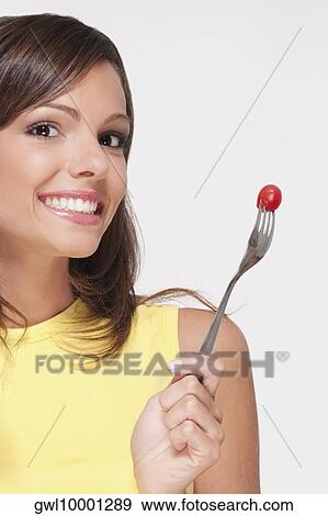 Portrait of a woman holding a cherry tomato on a fork View Large Photo Image Stock Photo - Portrait of a woman holding a cherry tomato on a fork. Fotosearch