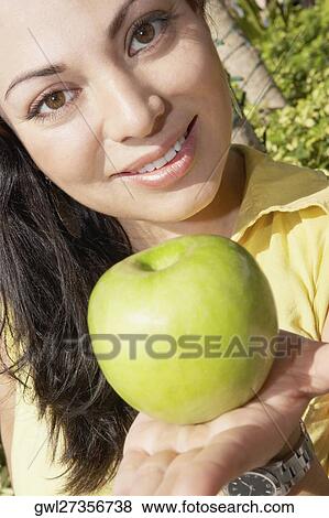 Stock Photo - Portrait of a woman holding a granny smith apple. Fotosearch