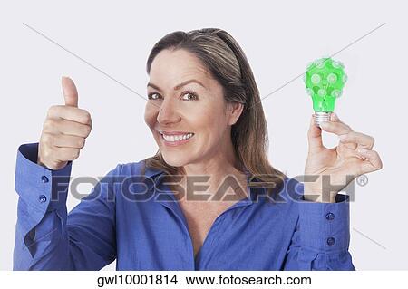 Portrait of a woman holding a green light bulb View Large Photo Image Picture - Portrait of a woman holding a green light bulb. Fotosearch