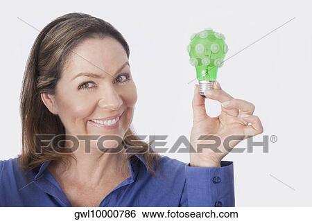 Stock Photograph - Portrait of a woman holding a green light bulb. Fotosearch