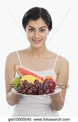Stock Photography - Portrait of a woman holding a plate of assorted fruits. Fotosearch