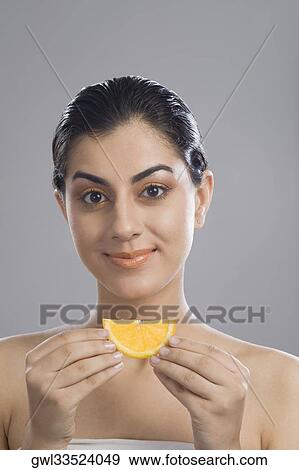 Portrait of a woman holding a slice of orange View Large Photo Image Stock Photo - Portrait of a woman holding a slice of orange. Fotosearch
