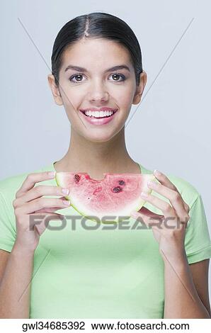 Stock Image - Portrait of a woman holding a watermelon slice. Fotosearch