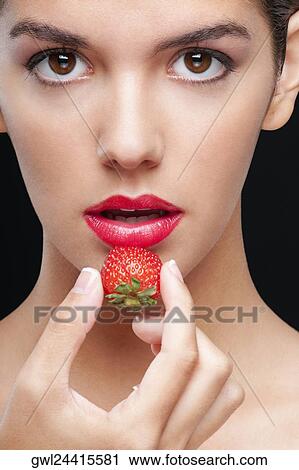 Stock Image - Portrait of a woman holding a strawberry. Fotosearch