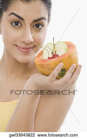 Portrait of a woman holding fruits inside a half of papaya View Large Photo Image Stock Image - Portrait of a woman holding fruits inside a half of papaya. Fotosearch
